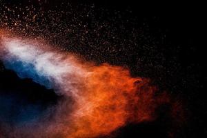 explosión de polvo azul naranja sobre fondo negro. nubes de salpicaduras de polvo de color azul naranja. foto
