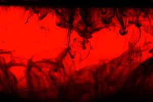 tinta alcrílica negra abstracta en agua sobre fondo rojo. patrón fractal colorido caótico de fantasía.