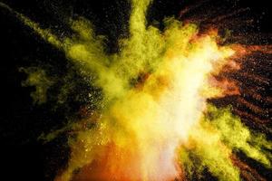 Abstract yellow powder explosion on black background.Freeze motion of yellow dust splash. photo