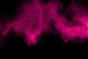 explosión de polvo de color rosa sobre fondo negro. salpicaduras de polvo de color sobre fondo oscuro.