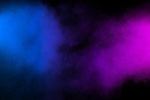 Pink blue powder explosion on black background.Pink blue dust splash cloud on dark background. photo