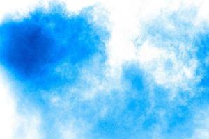 Bizarre forms of blue powder explode cloud on white background. Launched blue dust particles splashing. photo