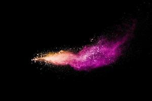 Freez motion of orange purple dust particle splash.Purple orange color powder explosion cloud  on black background. photo