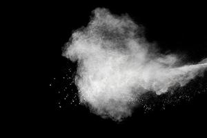 explosión de polvo blanco aislada sobre fondo negro. salpicaduras de partículas de polvo blanco. foto