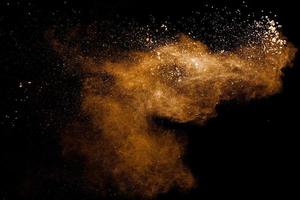 Abstract brown dust explosion on black background.Brown powder splashing. photo