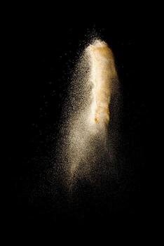 Launch brown particles exploding on black background. Brown dust splashing. photo