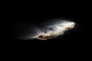 Sand explosion isolated on black background. Freeze motion of sandy dust splash. photo