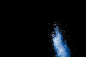 Abstract blue dust explosion on  black background. Blue powder splattered on black background. Freeze motion of blue powder splash. photo