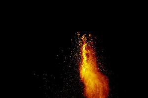 Red orange color powder explosion cloud isolated on black background. photo