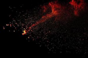 Red orange color powder explosion cloud isolated on black background. photo