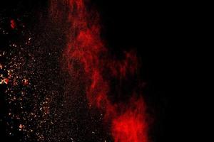 Red orange color powder explosion cloud isolated on black background. photo