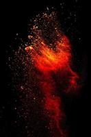 Red orange color powder explosion cloud isolated on black background. photo