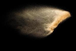 Abstract sand cloud.Golden colored sand splash agianst dark background.Yellow sand fly wave in the air. Sand explode on black background ,throwing freeze stop motion concept. photo