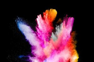 Multicolored powder explosion on black background.Color dust splash cloud on dark background.Launched colorful particles. photo