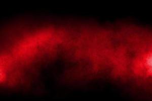 Red color powder explosion on black background.Freeze motion of red dust particles splashing. photo