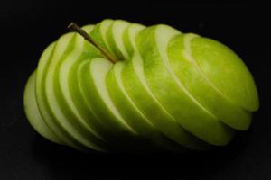 manzana verde fresca y en rodajas aisladas sobre fondo negro. foto