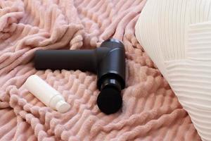 Blacl massage gun on bed read to use, lifestyle photo