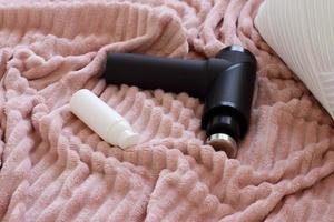 Blacl massage gun on bed read to use, lifestyle photo