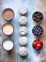 muffins with powdered sugar and almond, blackberry, strawberry, blueberry, yogurt, drink, chocolate milk on the wooden table photo