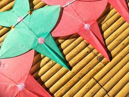 Flat lay of red and green star-shaped kites on bamboo litter, Thai art of craft concept photo