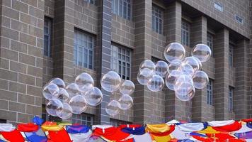 Selective focus at transparent balloons floating above various hanging clothes decorations against brick stone building background photo