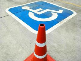 Red traffic cone and sign of wheelchair on the ground in hospital parking photo