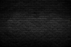 The old vintage black brick wall background with lighting decoration and dark tone style for background design concept photo