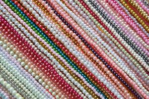 patrón de líneas diagonales de fondo de accesorios de collares de cuentas multicolores, patrón colorido de fila de cuentas de plástico en artesanías de moda foto