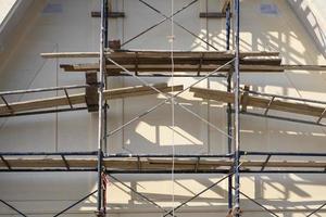 Sunlight and shadow on surface of metal scaffolding in front of roof truss structure under construction, renovation and improvement concept photo