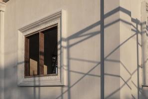 vista lateral del marco de la ventana con sombra de andamios en la superficie de la pared de hormigón en construcción en el sitio de construcción de viviendas foto