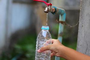 Young hand collecting water from an old water tap photo