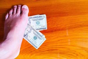 Men foot treads on money banknote. Dollars money. photo