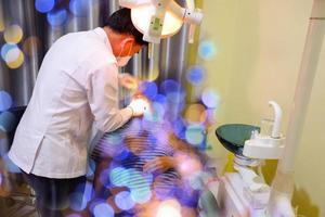 Male dentist in the dental office during the medical examination of patient. Selective focus. photo