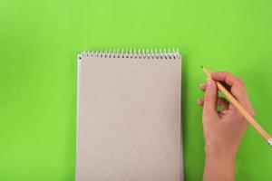 writting in the notebook with pencil on green background bussiness concept photo