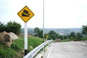 Warning traffic sign use low gear. The yellow road sign car down on the hill.