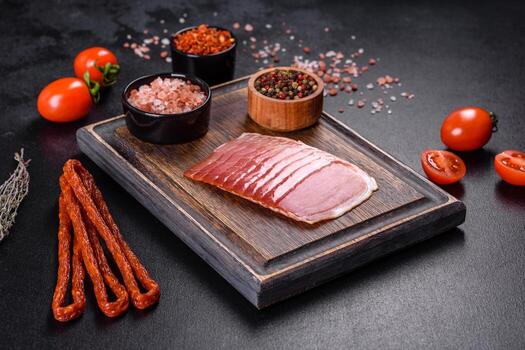 Smoked ham on a dark concrete table with addition of fresh aromatic herbs and spices photo