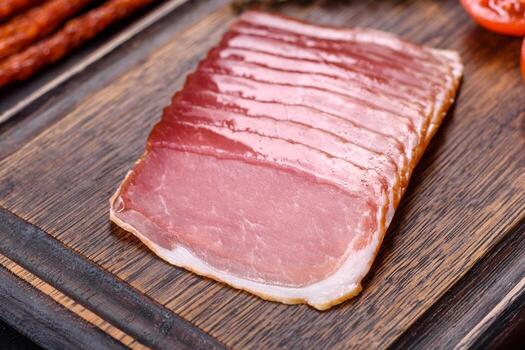 Smoked ham on a dark concrete table with addition of fresh aromatic herbs and spices photo