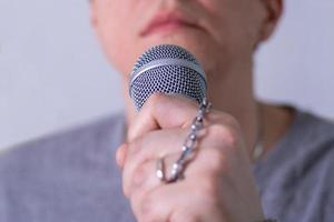 A man speaks into a microphone in close-up. photo