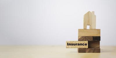 Pull out wooden block which print screen insurance wording with house on top for insurance asset protection concept. photo
