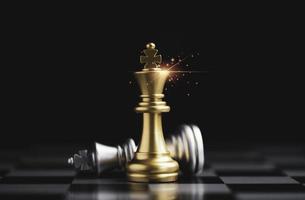 Golden king chess standing and silver king chess falling on chess board for the winner with competitor and business strategy concept.