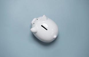Top view or flat lay of white piggy bank saving on blue background and copy space for deposit and money saving investment concept. photo
