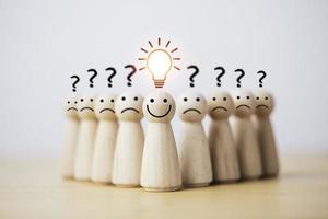 Smiley wooden human with light bulb and others human with question mark for creative thinking and problem solving solution concept. photo