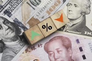 Increasing and decreasing percentage print screen to wooden cube block on Usd dollar and Yuan banknote for currency exchange rate concept. photo