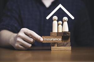 Family standing on wooden block  with hand pulling block which print screen insurance on it for assurance life and asset concept. photo