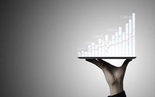 Trader holding Tablet and touching to technical graph chart  for analysis stock market data and speculator investment concept. photo