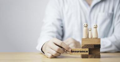 Businessman pull out wooden block which print screen insurance wording with wooden human on top for family insurance to make life security concept. photo