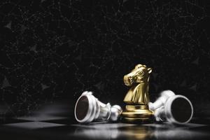 caballo dorado de primer plano o ajedrez de caballero con ajedrez de peón cayendo sobre fondo oscuro para el negocio ganador con el concepto de competidor y estrategia. foto