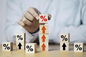 Businessman putting percentage sign which print screen on wooden cube block to up arrow for business profit and economic growth concept. photo