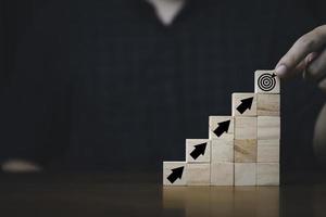 Hand putting and stacking virtual target board and arrow which print screen on wooden cube. Business achievement goal and objective target concept. photo