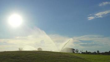 aspersor automático de agua a alta presión en el campo de golf que riega el césped, bomba de presión de la línea de agua retroiluminada video